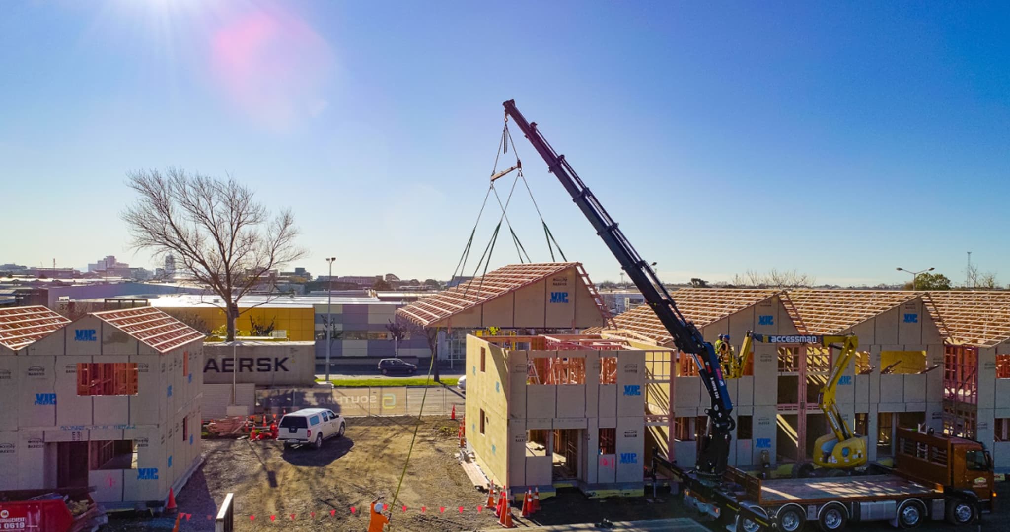 Crane lifting prefab truss made by VIP Frames & Trusses onto house frame on site